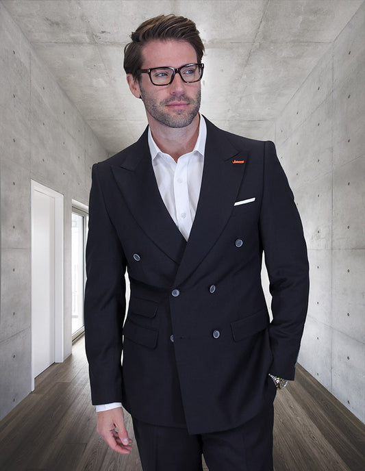 A man wearing glasses and the STATEMENT CLOTHING | SD-104-BLACK by Statement Clothing stands in a sleek, concrete hallway with wooden floors.