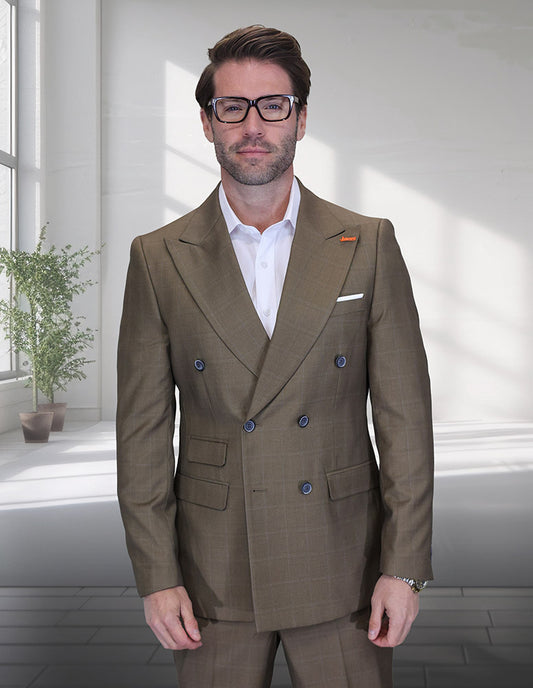 A man in the STATEMENT CLOTHING | SD-104-BRONZE double-breasted suit by Statement Clothing and a white shirt stands indoors near a sunlit window with a potted plant in the background.