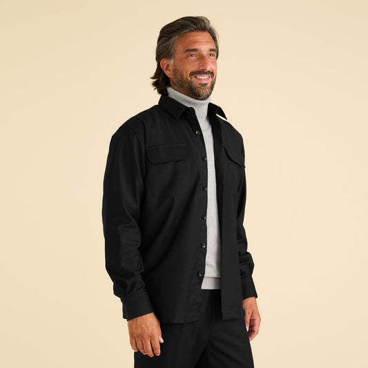 A man stands against a beige background wearing the Inserch Two-Pocket 2pc Set SE004-01 Black by Inserch over a light gray turtleneck sweater and black pants.