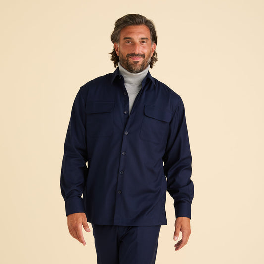 A man with medium-length brown hair and a beard models the Inserch Two-Pocket 2pc Set SE004-36 Ink by Inserch, featuring a navy shirt over a light gray turtleneck, paired with modern fit trousers, against a plain beige background.