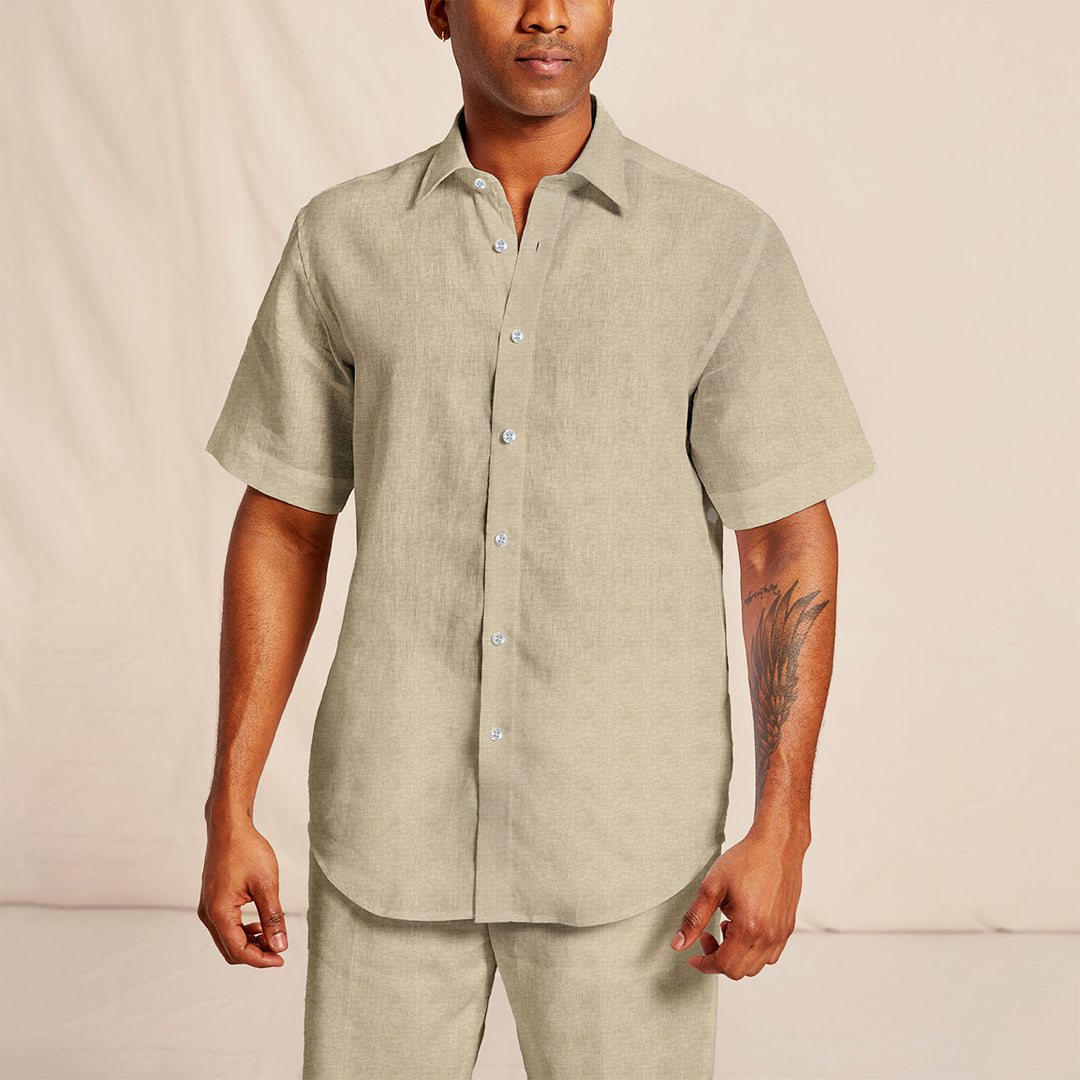 A man wearing an Inserch short-sleeve, button-up linen shirt (SS717-00006 in Oatmeal) with matching pants and a tattoo on his right arm.
