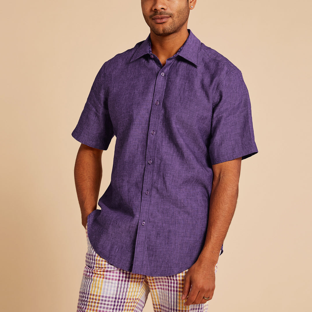 A man in an Inserch SS Linen Shirt SS717-00068 Eggplant and plaid shorts stands against a beige background.