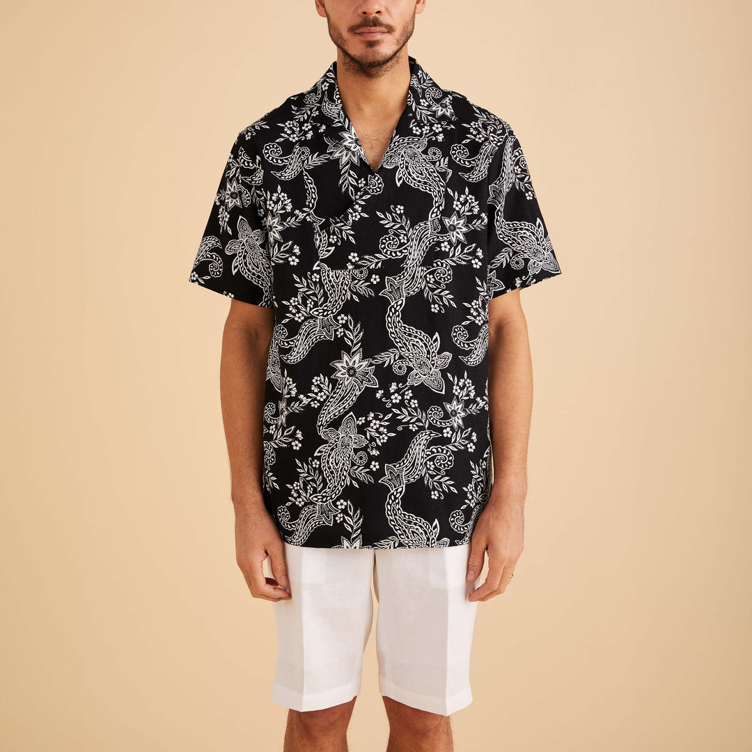 A man wears the Inserch SS Linen Pull Over Shirt (SS81315-00149) in black/white floral paisley print with white shorts, set against a beige background.