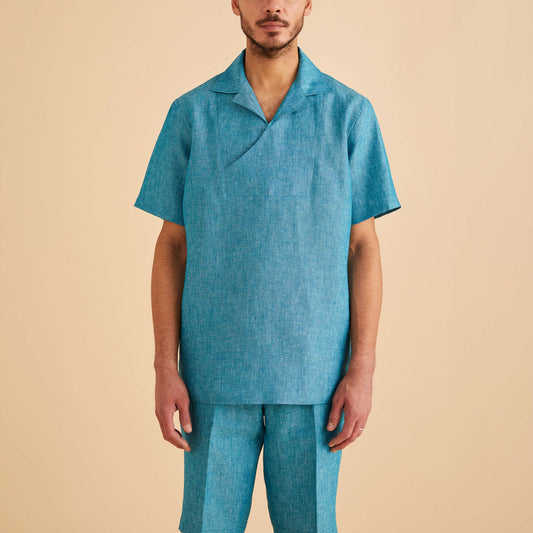 A man wears the Inserch Linen Pull Over Shirt SS813-00172 Caspian in turquoise with matching shorts, standing against a beige background.