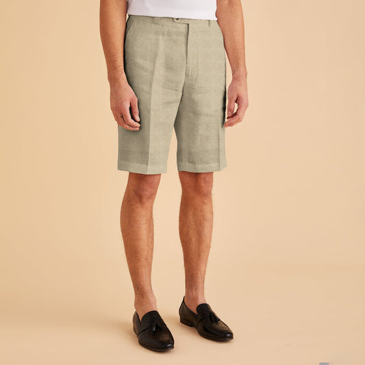 A person wearing Inserch Modern Linen Shorts ST31-00006 Oatmeal, a white shirt, and black loafers stands against a beige background, showcasing a modern fit.