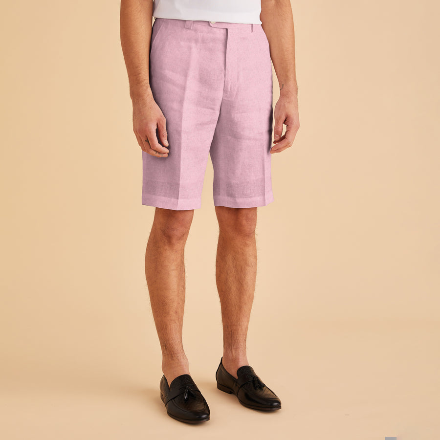 A person wearing Inserch Modern Linen Shorts in Desert Rose and black loafers stands against a beige background, showcasing a modern fit.