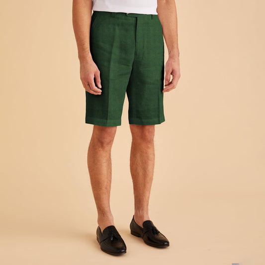 An individual wearing a modern-fit white shirt, Inserch Modern Linen Shorts ST31-00200 Emerald, and black shoes stands against a beige background.