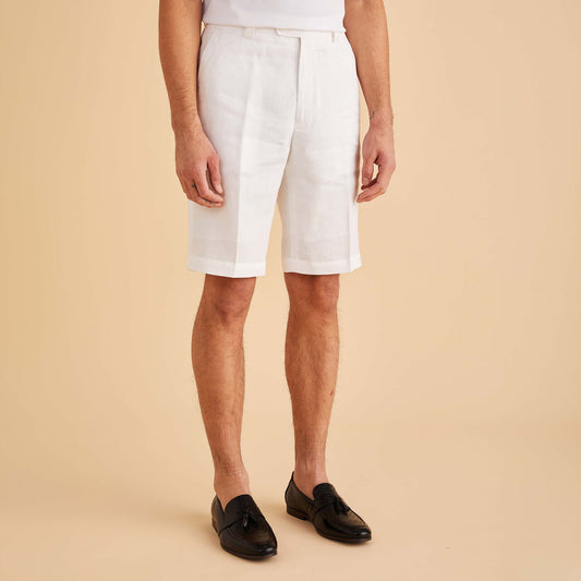 A person in polished style poses against a beige background, wearing Inserch Modern Linen Shorts ST31-00002 in white, which have a 34” inseam, paired with sleek black loafers.