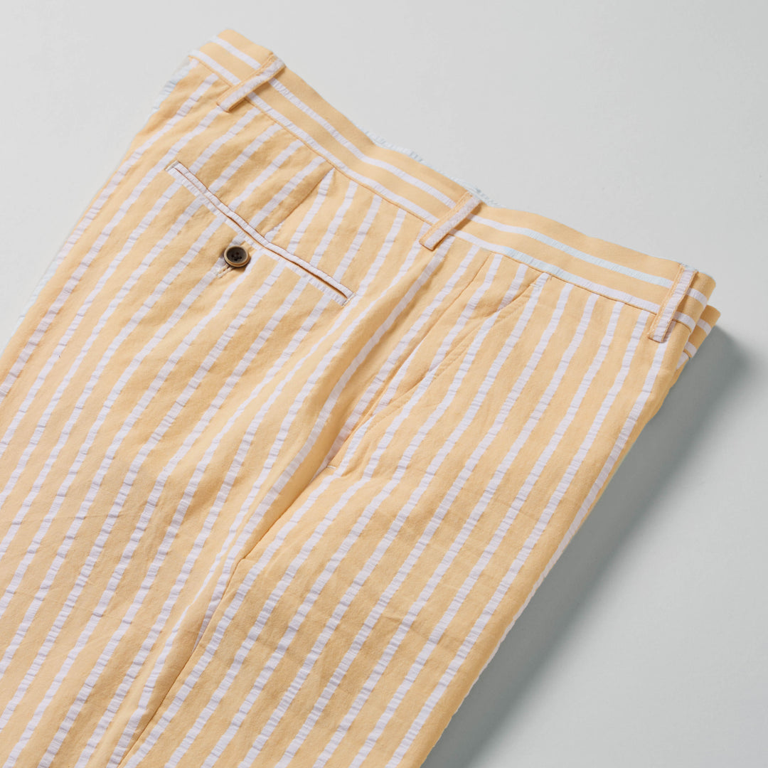 Close-up of the Inserch Wide Stripe Seersucker Suit in Yuzu—a modern tailored fit beige blazer with white vertical stripes, brown buttons, and two front pockets by Inserch.