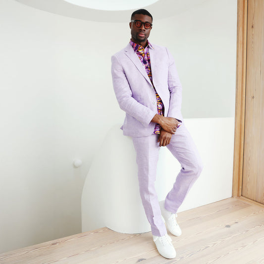 A man wearing the Inserch Slim Linen Blazer SU880-00119 in lavender, paired with a matching shirt and brown dress shoes, stands against a beige background.