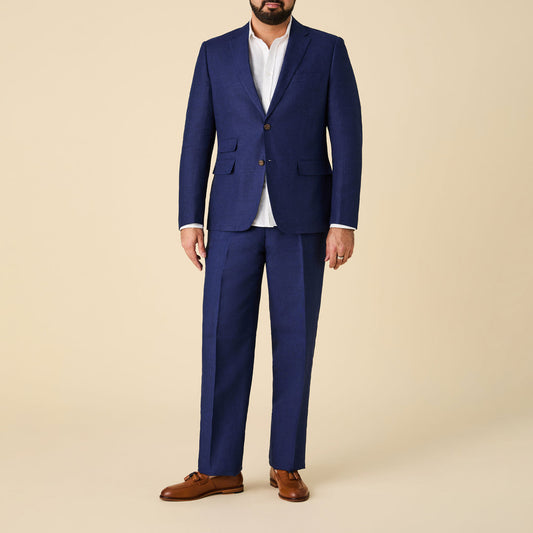 A man stands against a beige background wearing an Inserch Slim Linen Blazer SU880-00150 Summer Navy over a white dress shirt and brown dress shoes.