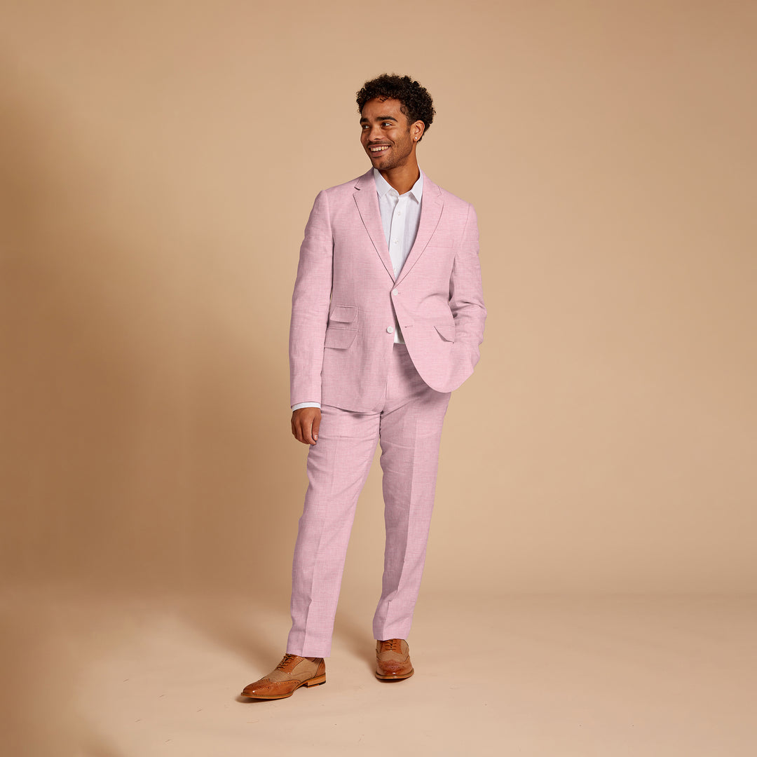 The man in an Inserch Slim Linen Suit SU880-00193 Desert Rose pairs it with a white shirt and brown shoes, smiling against a beige background.