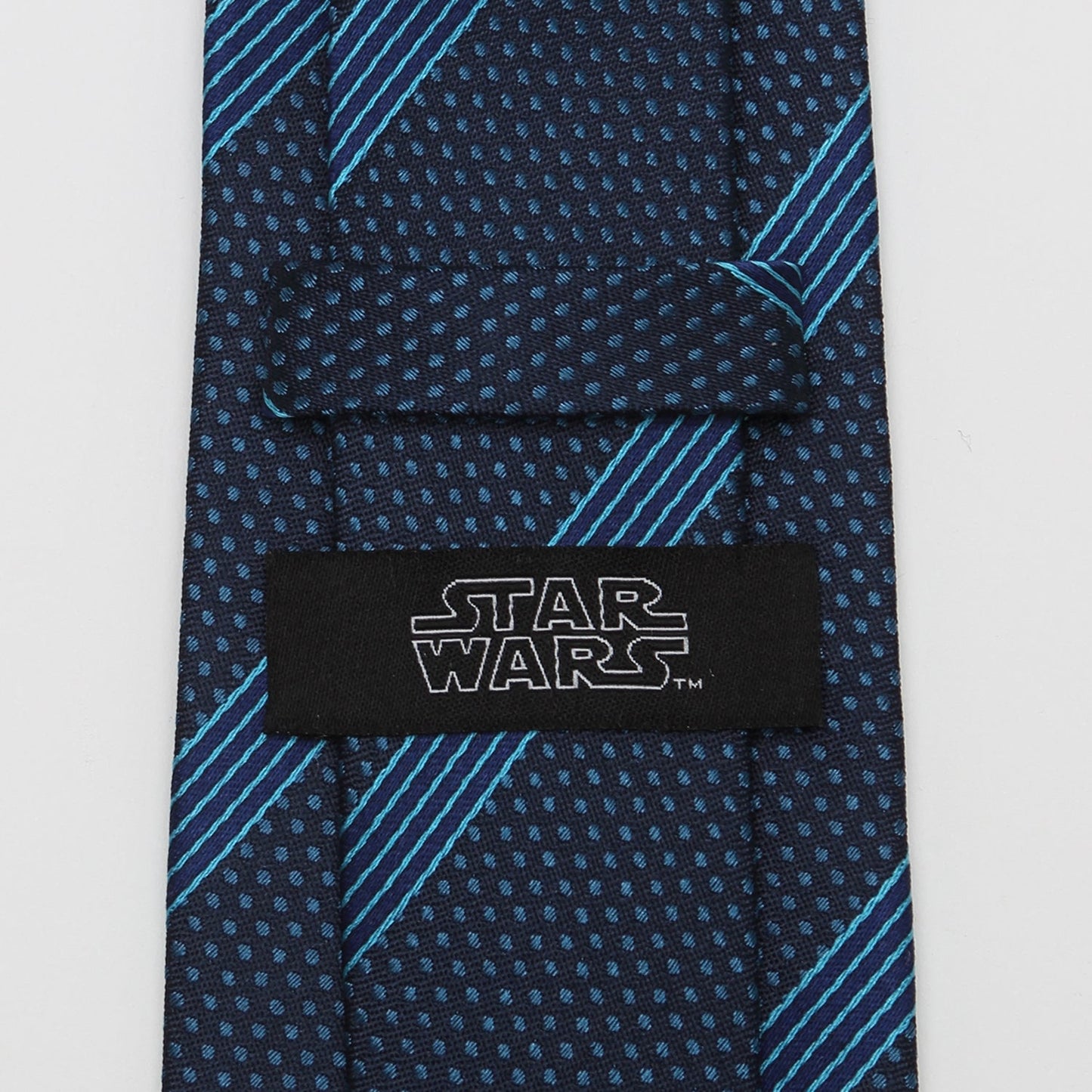 The Star Wars Millennium Falcon Blue Striped Tie by Cufflinks.com features navy blue fabric with light blue polka dots and diagonal stripes, shown rolled up on a white background.