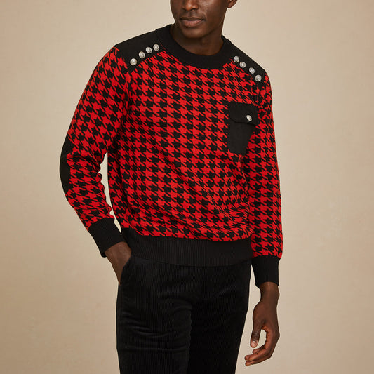 A man wears the Inserch Cotton Blend Houndstooth Crew Neck Sweater SW002-30 Red, featuring a red and black houndstooth pattern, shank buttons on the shoulders, a black chest pocket, and black trim.