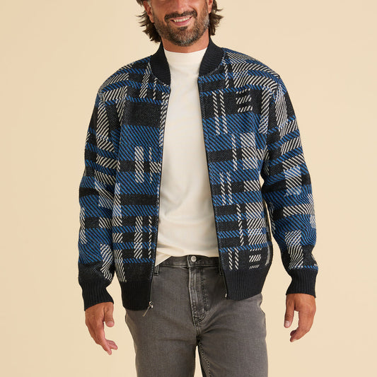 A man smiles against a beige background, wearing the Inserch Geometric Full Zip Baseball Knit Jacket SW609-11 Navy over a white shirt and gray jeans.