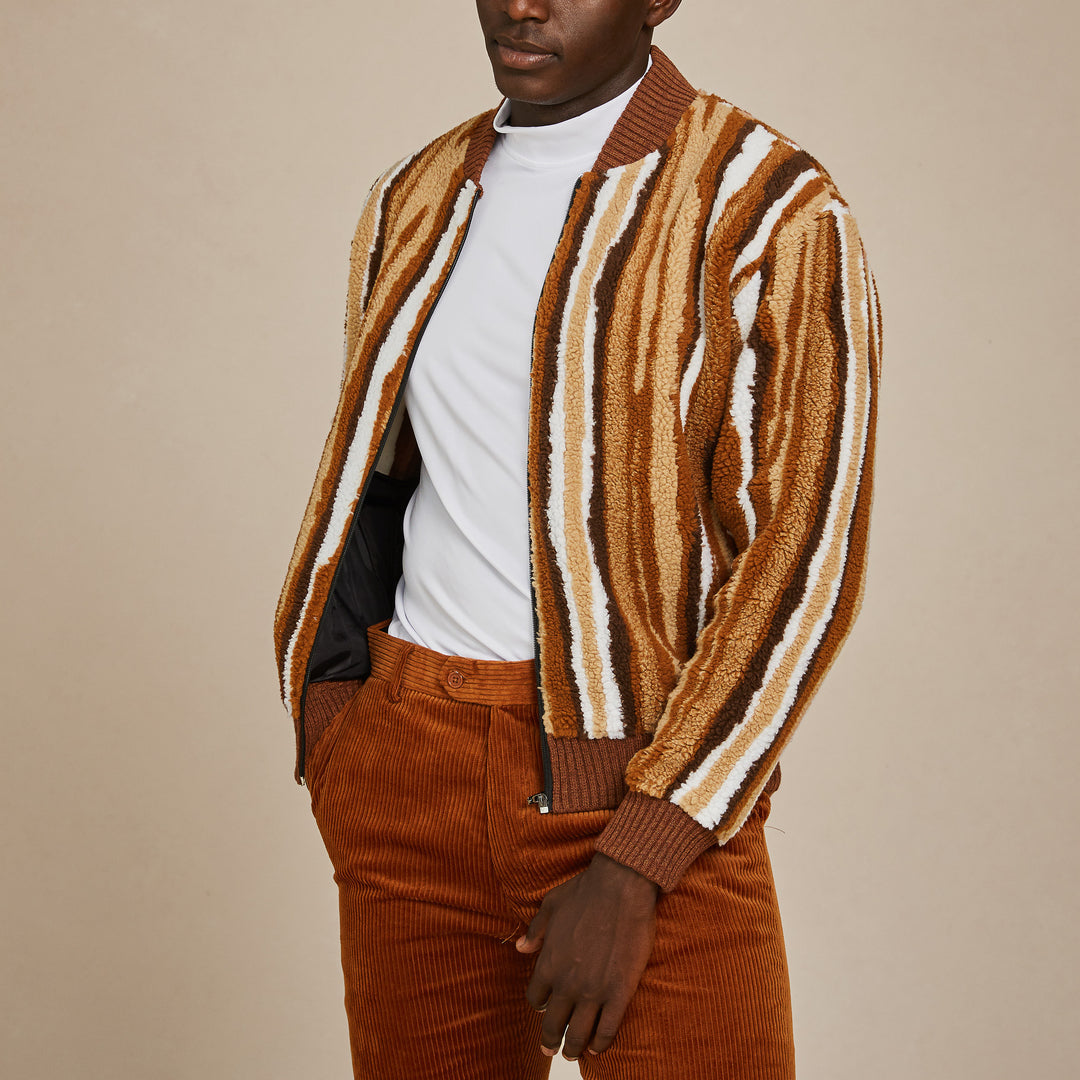 A man wears the Inserch Stripe Baseball Sweater Jacket SW610-121 Earth by Inserch over a white shirt with brown corduroy pants, standing against a plain beige background.