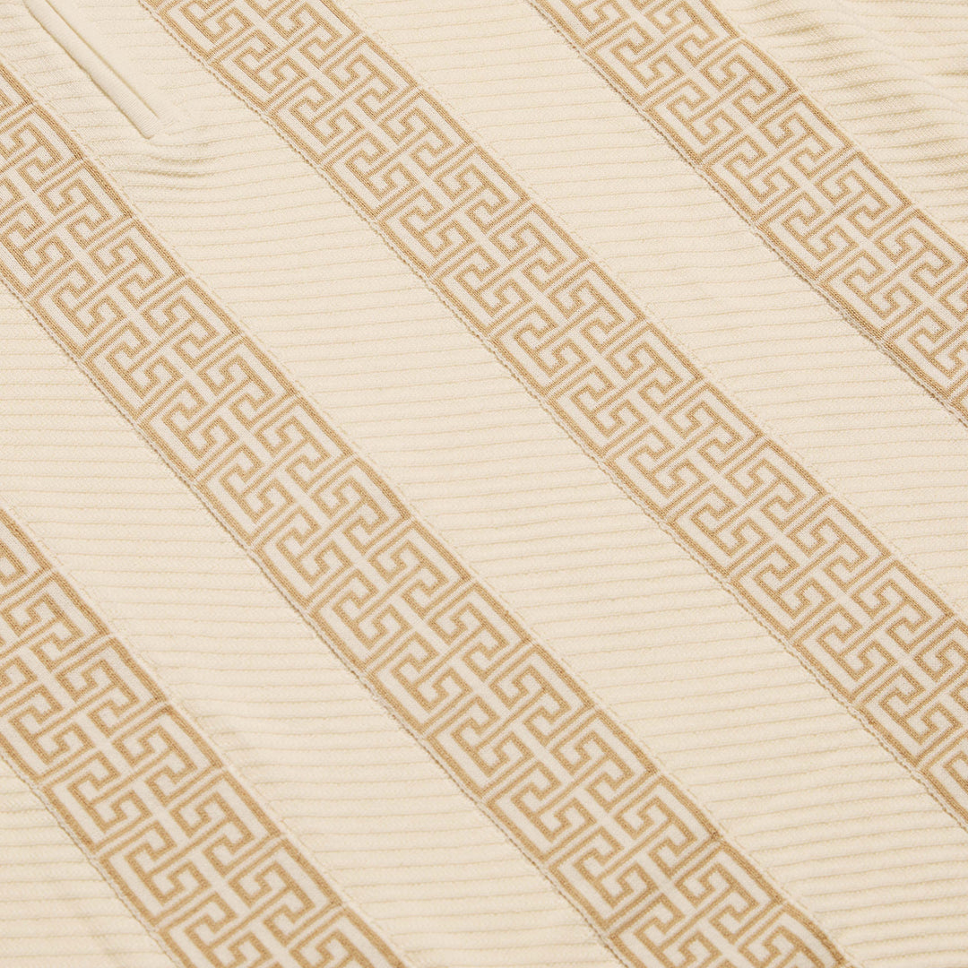 A man wearing the Inserch Grecian Intarsia Half Zip Sweater (SW615-00134 Bone) stands in front of a white bookshelf filled with books and decor.