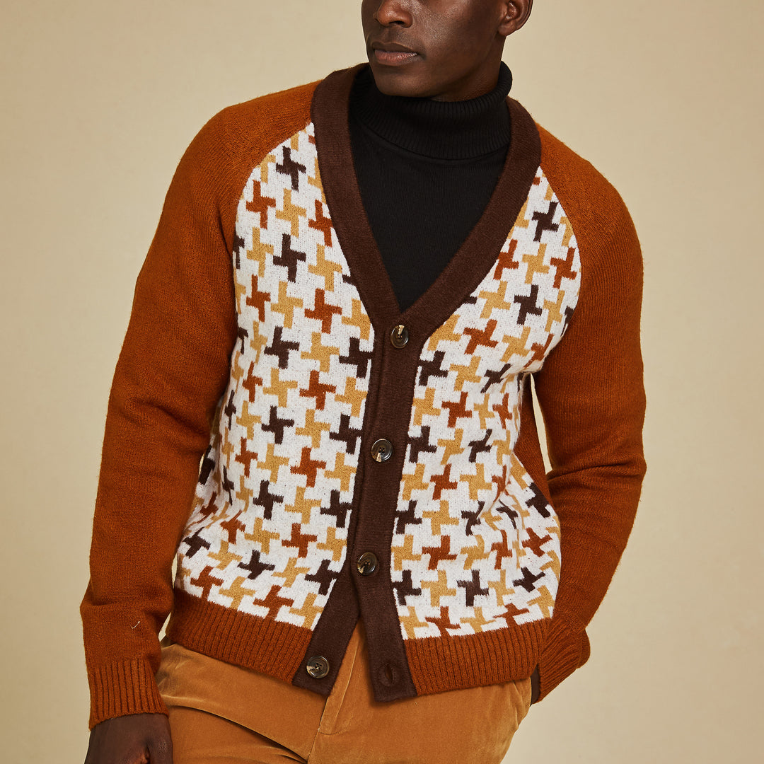 A man wears the Inserch Houndstooth Pattern Cardigan SW906-05 Caramel over a black turtleneck and tan pants, standing against a beige background.