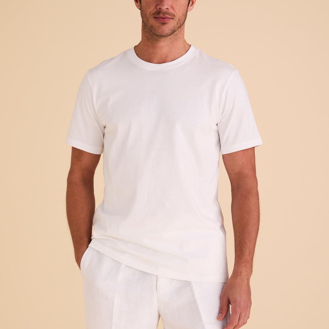 A man in an Inserch Short Sleeve Pima Cotton T-Shirt T301-00002 White and light-colored pants stands against a beige background.
