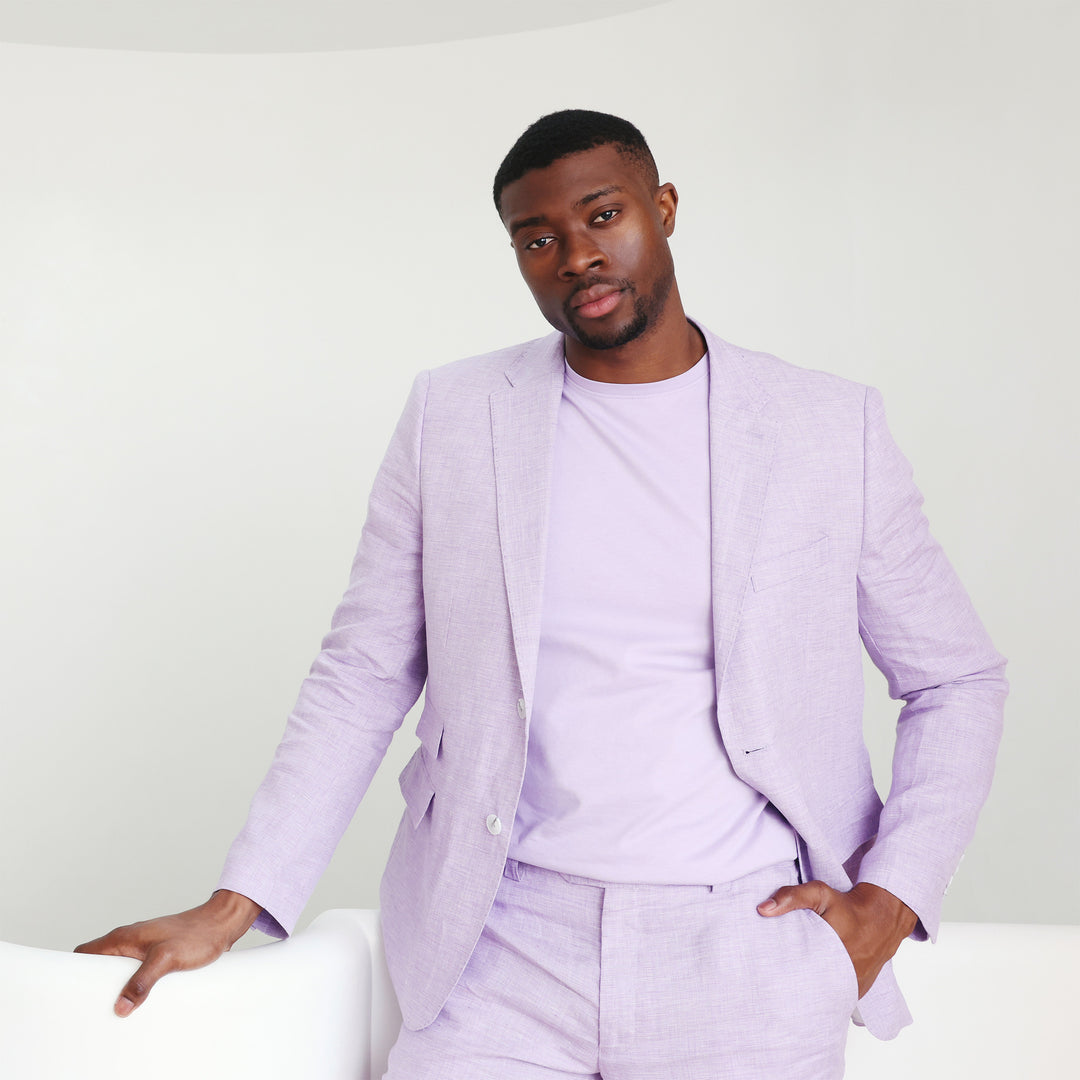 A person wearing an Inserch Short Sleeve Pima Cotton T-Shirt T301-00119 in lavender and white pants stands against a beige background, with hands in pockets, gazing to the side.