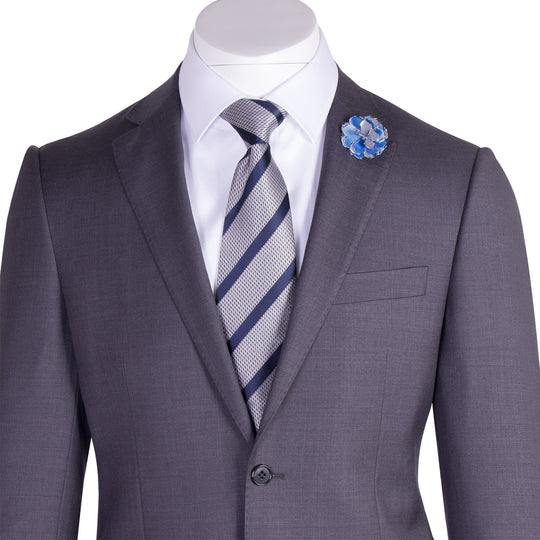 The Tiglio Luxe Novello Medium Gray Pure Wool Men’s Suit TIG1008 features a white dress shirt, striped tie, blue flower lapel pin, and a left sleeve label—Tiglio Luxe luxury fashion for men, displayed on a headless mannequin.