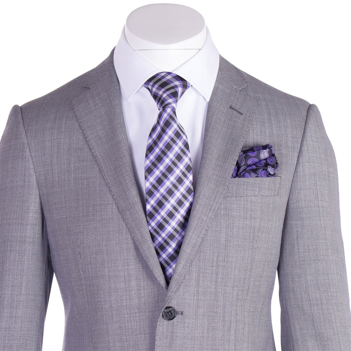 The Tiglio Luxe Novello Light Gray Birdseye Pure Wool Men’s Suit TIG1018 by Tiglio Luxe is showcased on a mannequin, featuring classic notch lapels, a crisp white dress shirt, and complemented by a purple plaid tie with a matching pocket square—an elegant ensemble that exemplifies the sophistication of Italian-inspired men’s tailoring.