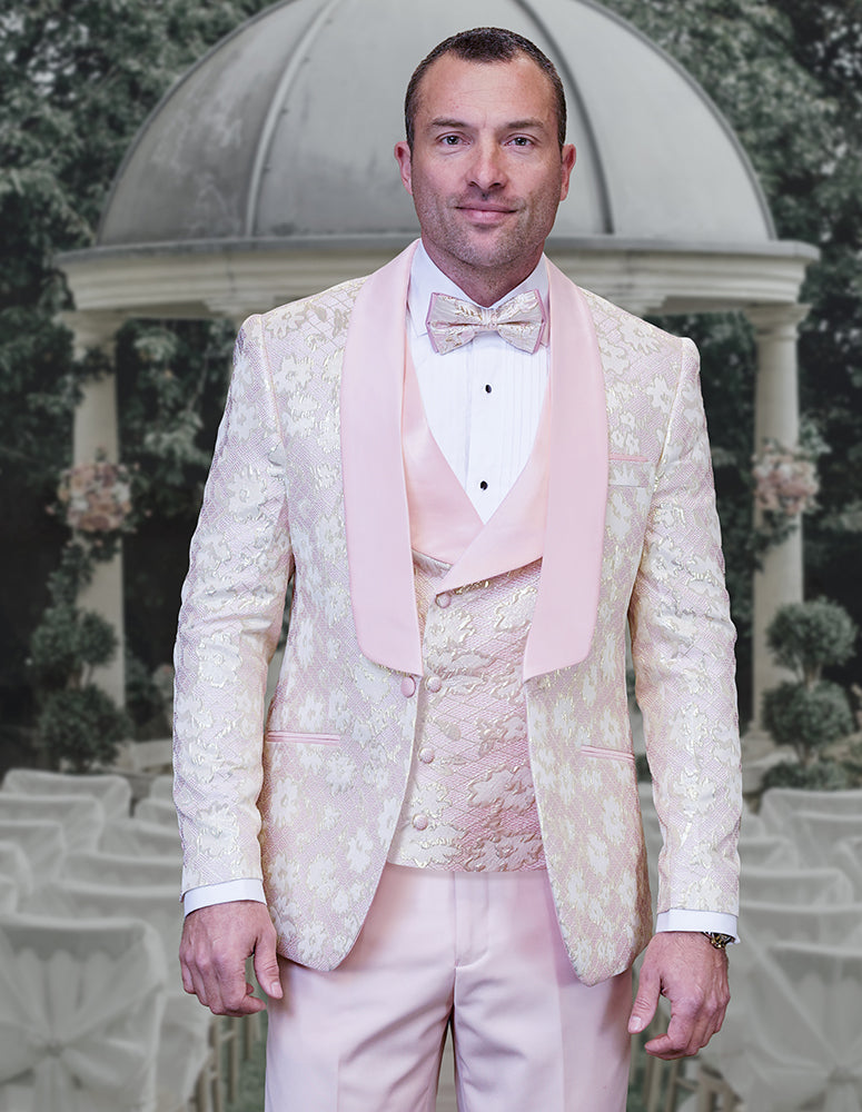 A man wears the STATEMENT CLOTHING | TIZANO-BLUSH modern fit tuxedo by Statement Clothing, complete with a matching bow tie, standing before an outdoor wedding setup with a white pavilion and chairs.
