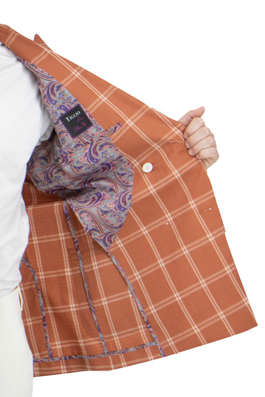 A person embracing sartorial traditions in a Tiglio Luxe Slim Fit Half Lined Pure Wool Jacket TL2632, featuring a burnt orange with off-white windowpane pattern over a crisp white dress shirt and trousers.