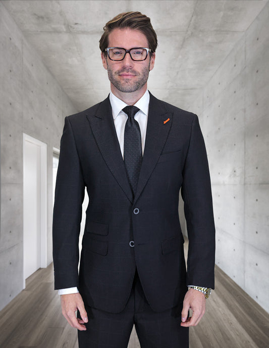 A man in a modern fit, double-breasted TRIESTE-BLACK suit by Statement Clothing stands in a concrete-walled hallway, looking at the camera.