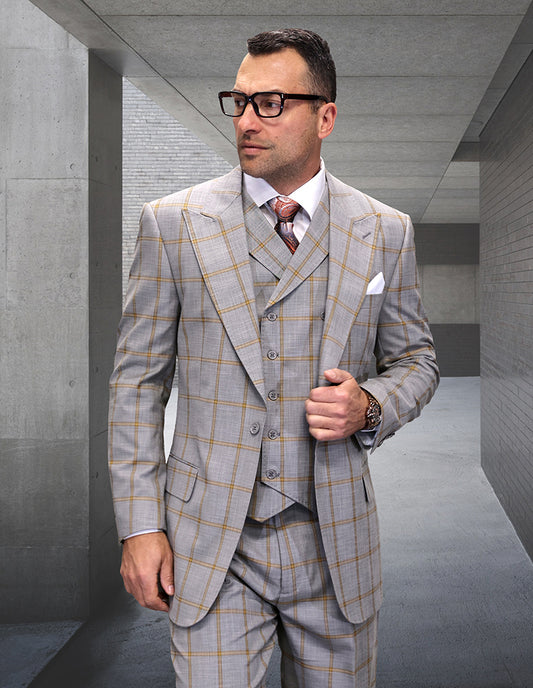 A man wearing the STATEMENT CLOTHING | TUSCANY-TAN three-piece suit by Statement Clothing stands in a modern concrete hallway, looking to the side.