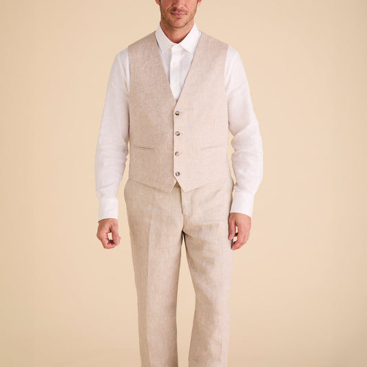 A person stands wearing the Inserch Classic Linen Vest V660-00006 Oatmeal with matching pants, paired with a white long-sleeve shirt, set against a plain beige background.