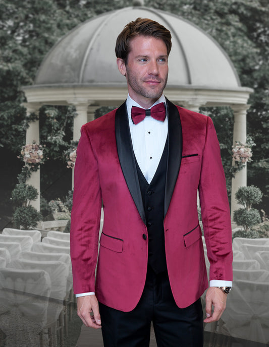 Wearing the STATEMENT CLOTHING | VL-100-BURGUNDY suit by Statement Clothing, a man stands in front of an outdoor wedding venue, embodying tailored elegance with burgundy velvet and black lapels.