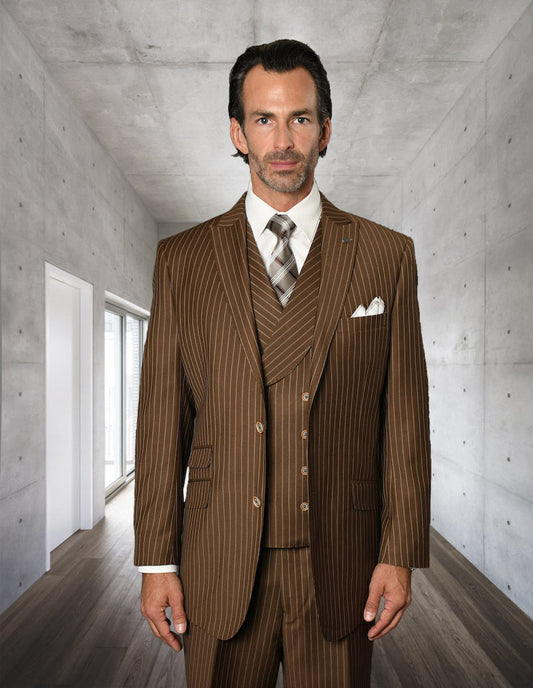 A man wearing the STATEMENT CLOTHING | ZARELLI-BRONZE suit by Statement Clothing stands in a modern hallway with concrete walls and wood flooring.