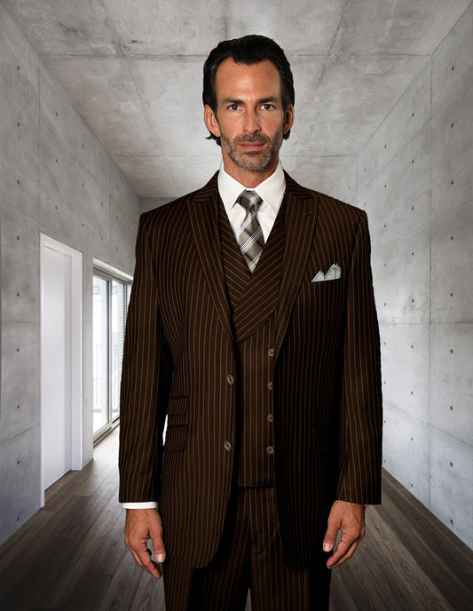 A man wears the STATEMENT CLOTHING | ZARELLI-BROWN pinstripe suit with pleated pants by Statement Clothing, standing in a sleek concrete hallway with wooden floors and a window on the left.