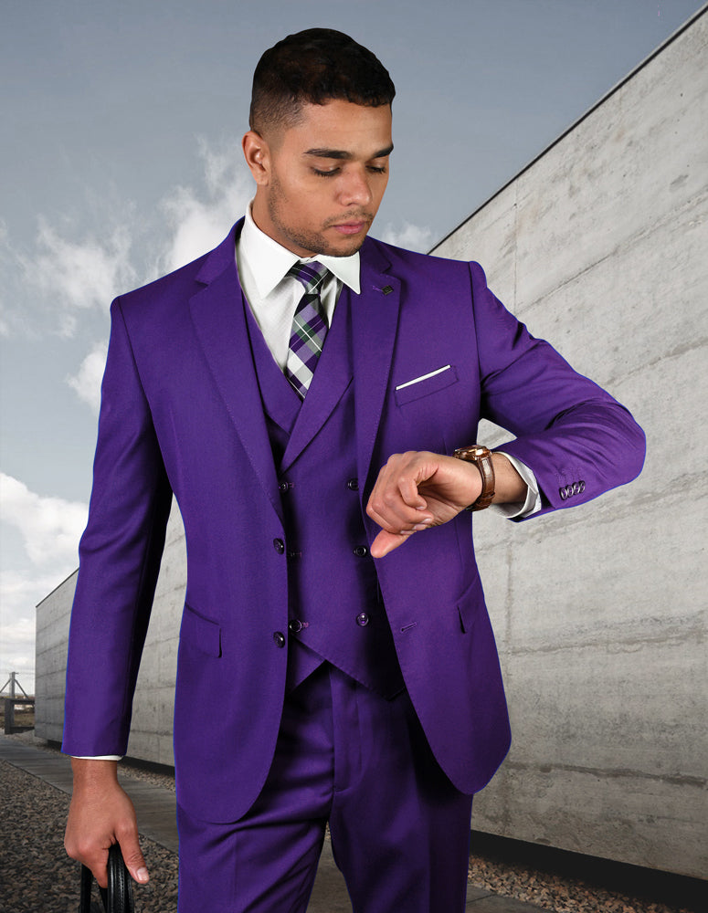 A man in the STATEMENT CLOTHING | ZARGALA-PURPLE modern fit suit by Statement Clothing checks his watch outside a sleek concrete building, holding a black bag and wearing an Italian wool double breasted vest.