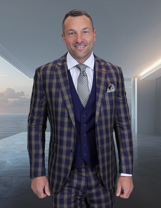 A man wearing the STATEMENT CLOTHING | ZILONI-1-MIDNIGHT blue and yellow plaid Italian wool suit by Statement Clothing, paired with a white shirt and patterned tie, stands indoors against a modern, minimalist background.