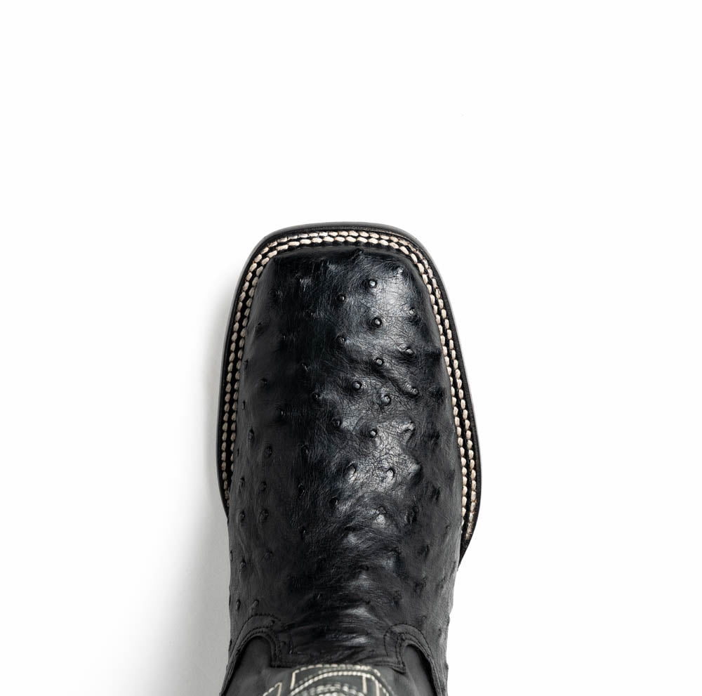 The Alabama Black by Marco Di Milano: a pair of black ostrich skin cowboy boots with white stitching, shown from side and sole views. These luxury men's boots combine classic western style with superb craftsmanship.