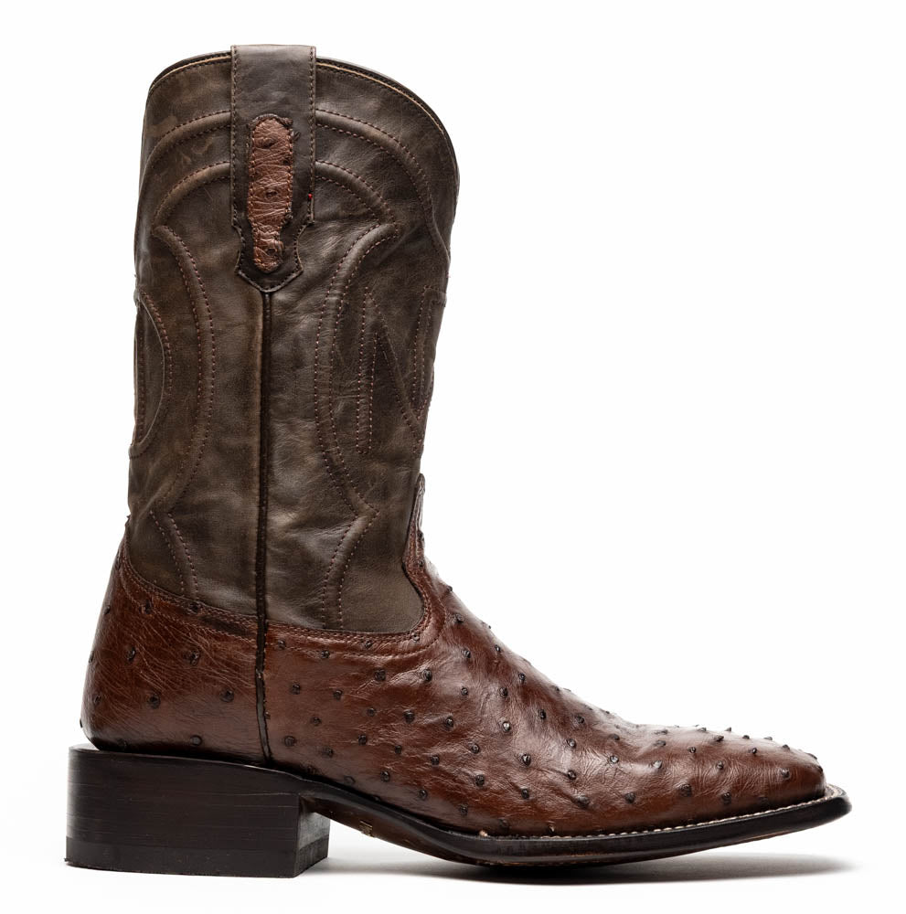 A pair of Marco Di Milano Alabama Kango Tabac men’s boots, handcrafted with genuine ostrich skin foot and dark upper, one upright and one displaying the branded sole, showcase classic Western cowboy style.