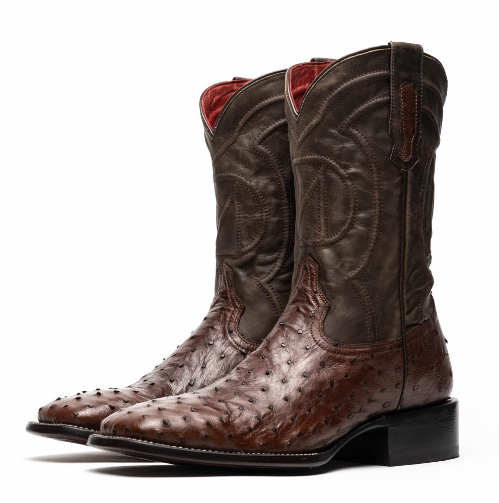 A pair of Marco Di Milano Alabama Kango Tabac men’s boots, handcrafted with genuine ostrich skin foot and dark upper, one upright and one displaying the branded sole, showcase classic Western cowboy style.