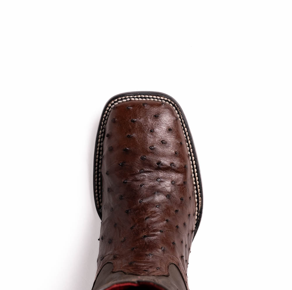 A pair of Marco Di Milano Alabama Kango Tabac men’s boots, handcrafted with genuine ostrich skin foot and dark upper, one upright and one displaying the branded sole, showcase classic Western cowboy style.