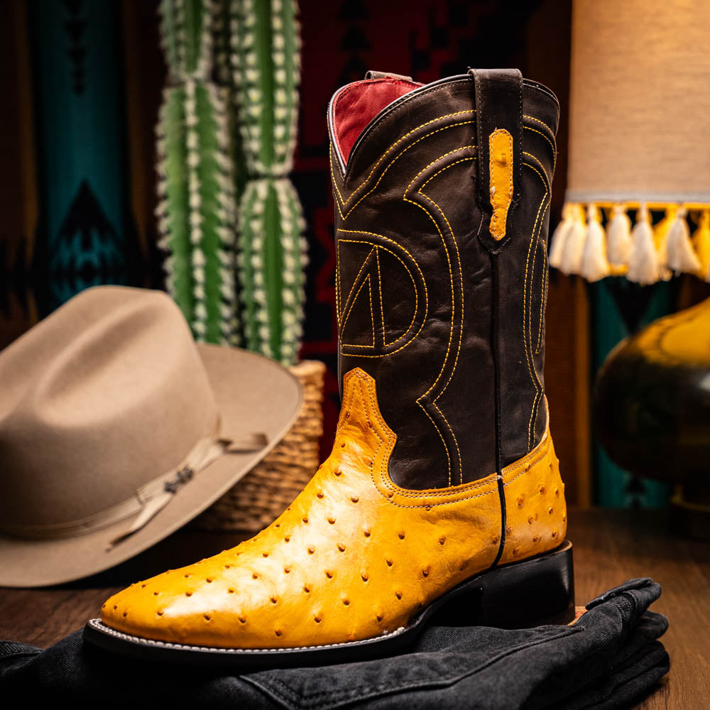 Introducing the Alabama Buttercup by Marco Di Milano: handcrafted cowboy boots with yellow genuine ostrich skin on the foot, dark brown leather shafts, and signature branding embossed on the sole.