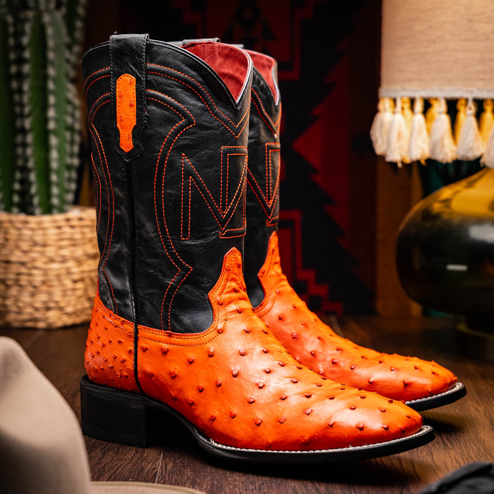 A pair of Alabama Orange cowboy boots by Marco Di Milano featuring a textured orange and black genuine ostrich upper and a visible logo on the leather sole.