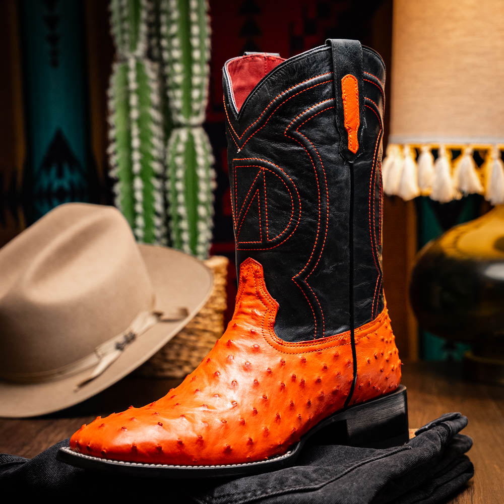 A pair of Alabama Orange cowboy boots by Marco Di Milano featuring a textured orange and black genuine ostrich upper and a visible logo on the leather sole.