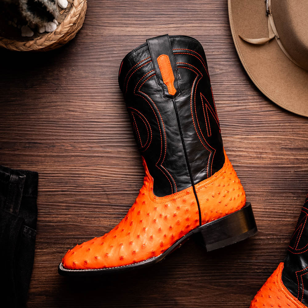 A pair of Alabama Orange cowboy boots by Marco Di Milano featuring a textured orange and black genuine ostrich upper and a visible logo on the leather sole.