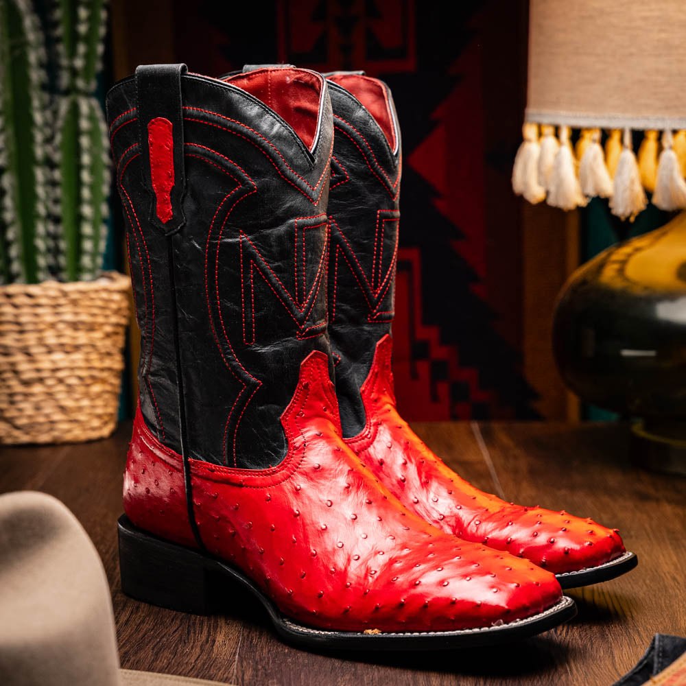 The Marco Di Milano Alabama Red boots feature handcrafted red and black textured leather; one stands upright while the other reveals the branded sole—a modern take on classic Western style.