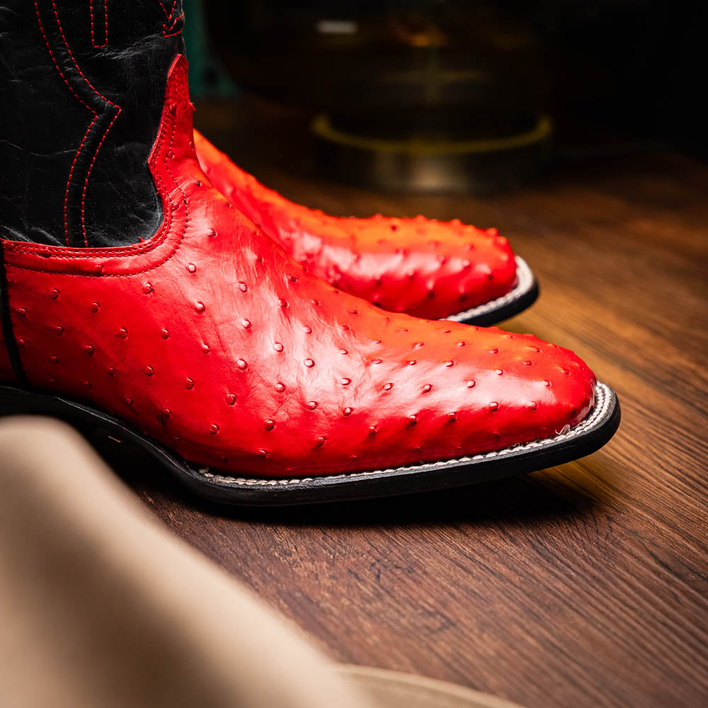 The Marco Di Milano Alabama Red boots feature handcrafted red and black textured leather; one stands upright while the other reveals the branded sole—a modern take on classic Western style.