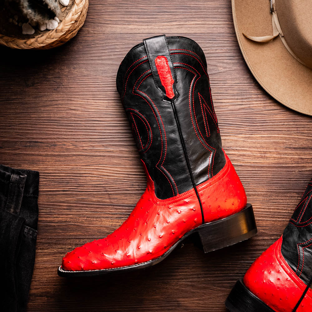 The Marco Di Milano Alabama Red boots feature handcrafted red and black textured leather; one stands upright while the other reveals the branded sole—a modern take on classic Western style.