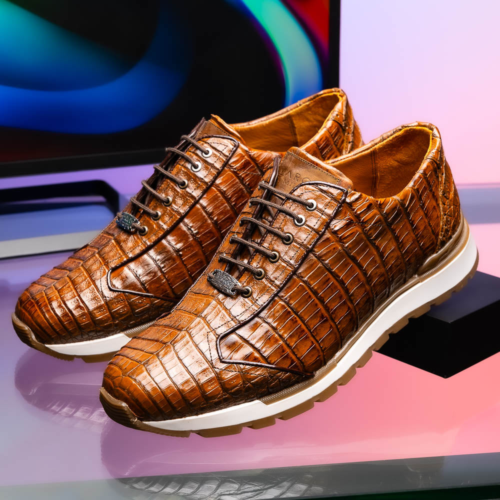 The Marco Di Milano Alonzo Bay Apache sneakers feature brown genuine caiman crocodile leather, white midsoles, brown rubber outsoles, a lace-up design, and a textured pattern—luxury footwear ideal for any occasion.