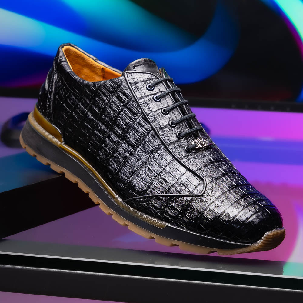 The Alonzo Black by Marco Di Milano: luxury men's sneakers crafted from black genuine caiman crocodile leather with a hand-painted finish and brown rubber soles—one shoe upright, the other leaning against it.