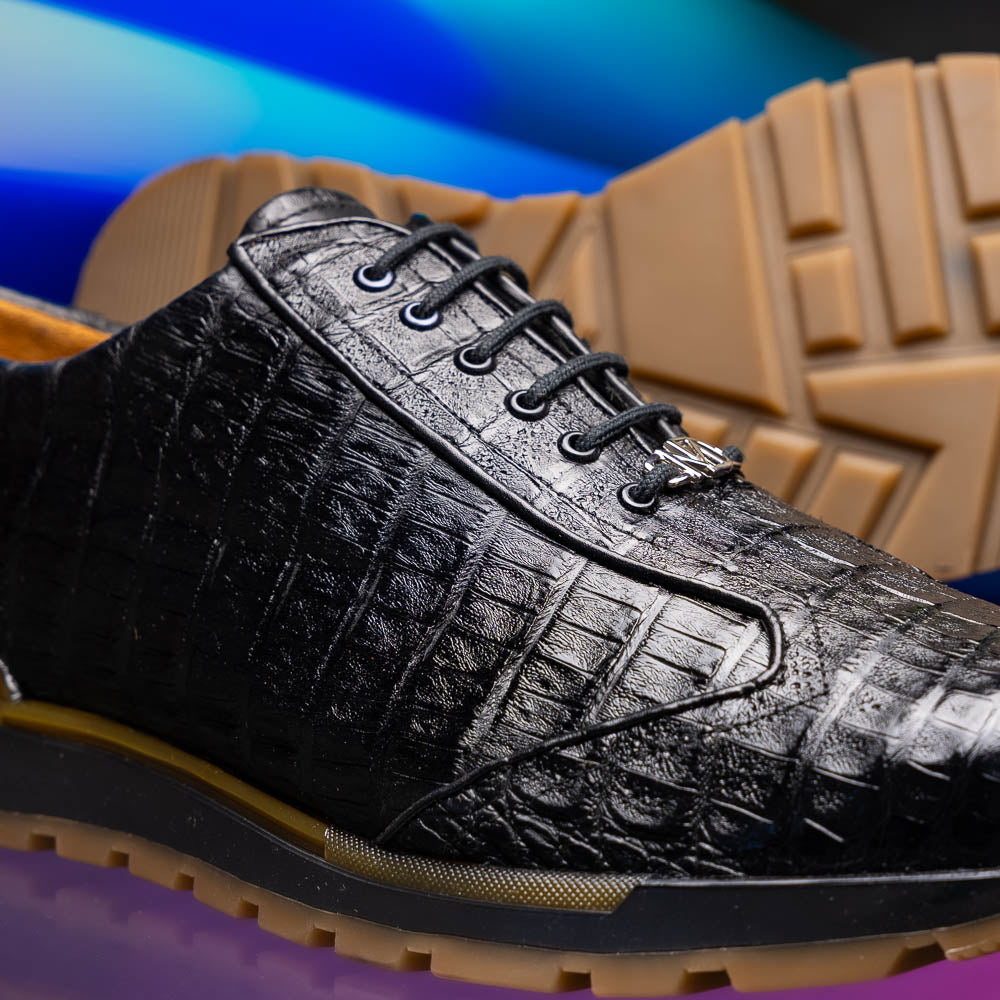 The Alonzo Black by Marco Di Milano: luxury men's sneakers crafted from black genuine caiman crocodile leather with a hand-painted finish and brown rubber soles—one shoe upright, the other leaning against it.